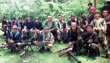 Abu Sayyaf leaders Khaddafi Janjalani, 2nd from left in front row, and Radulan Sahiron, 2nd from right in front row with headband, sit with fellow Abu Sayyaf rebels inside their jungle hideout somewhere in the area of Sulu province in the southern Philippines on Sunday July 16, 2000. It was the first time Janjalani allowed a photograph since they fled to Sulu from nearby Basilan island following their kidnapping of more than 50 people most of whom were school children. (AP Photo/STR)